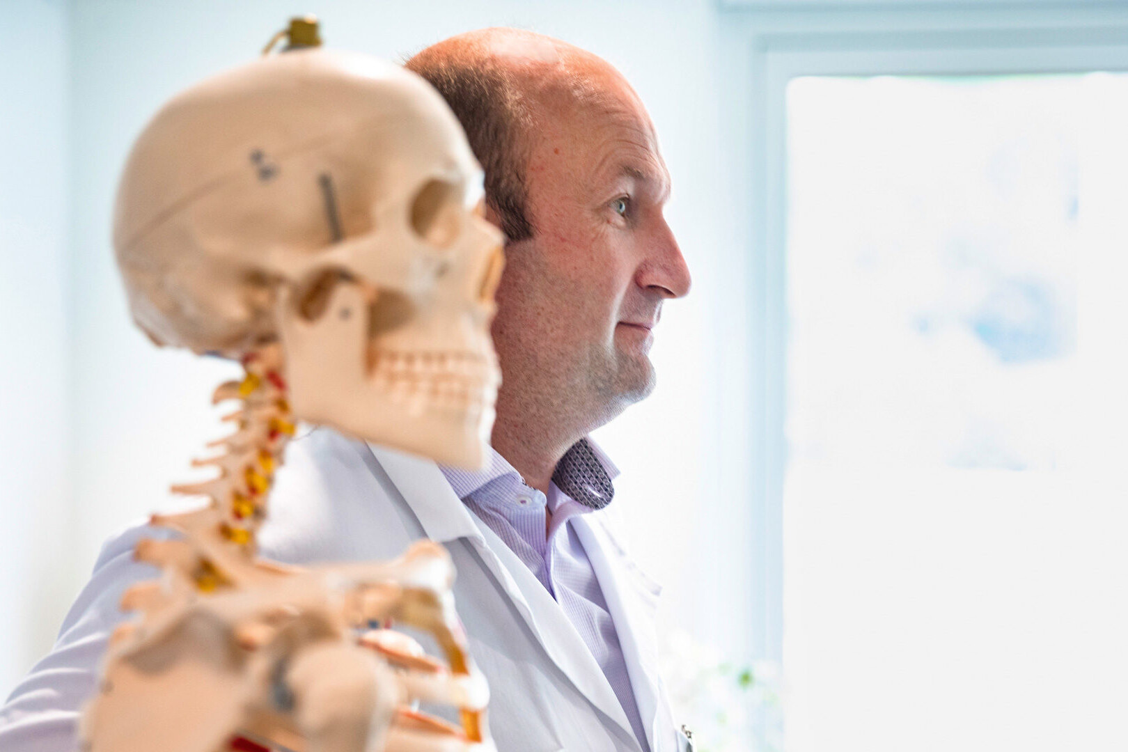 Dr. med. Michael Schmelz, Unfallchirurg, neben einem Schulungsskelett.