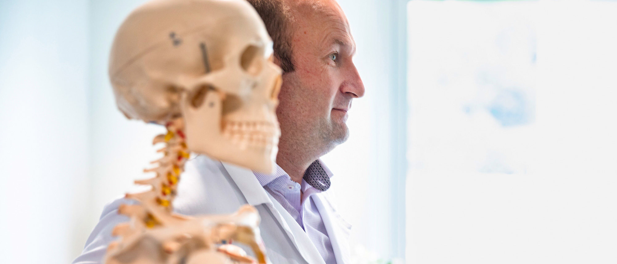 Dr. med. Michael Schmelz, Unfallchirurg, neben einem Schulungsskelett.